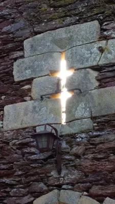 Steinmauer mit glühend leuchtendem Kreuz aus Glas