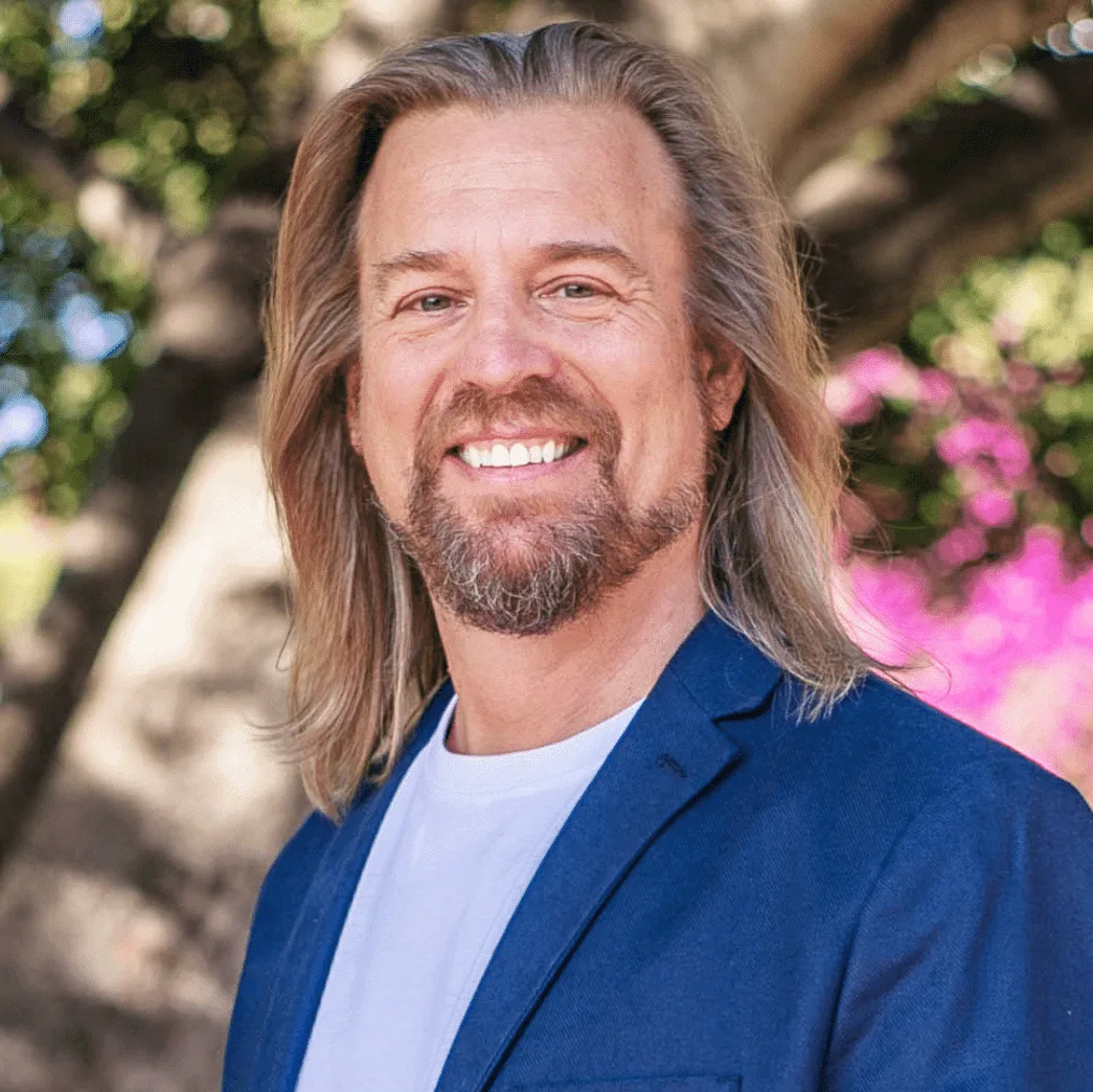 Porträt von Dr. Marc Stollreiter mit langen braunen Haaren und Bart