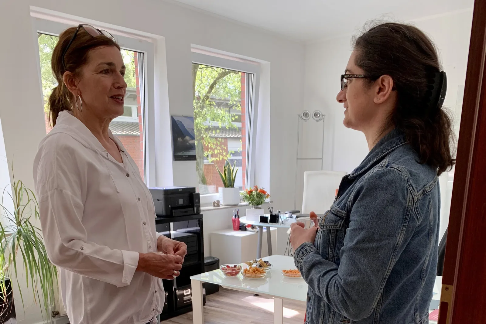 Zwei Frauen im Dialog in gemütlichem Büro mit Snacks