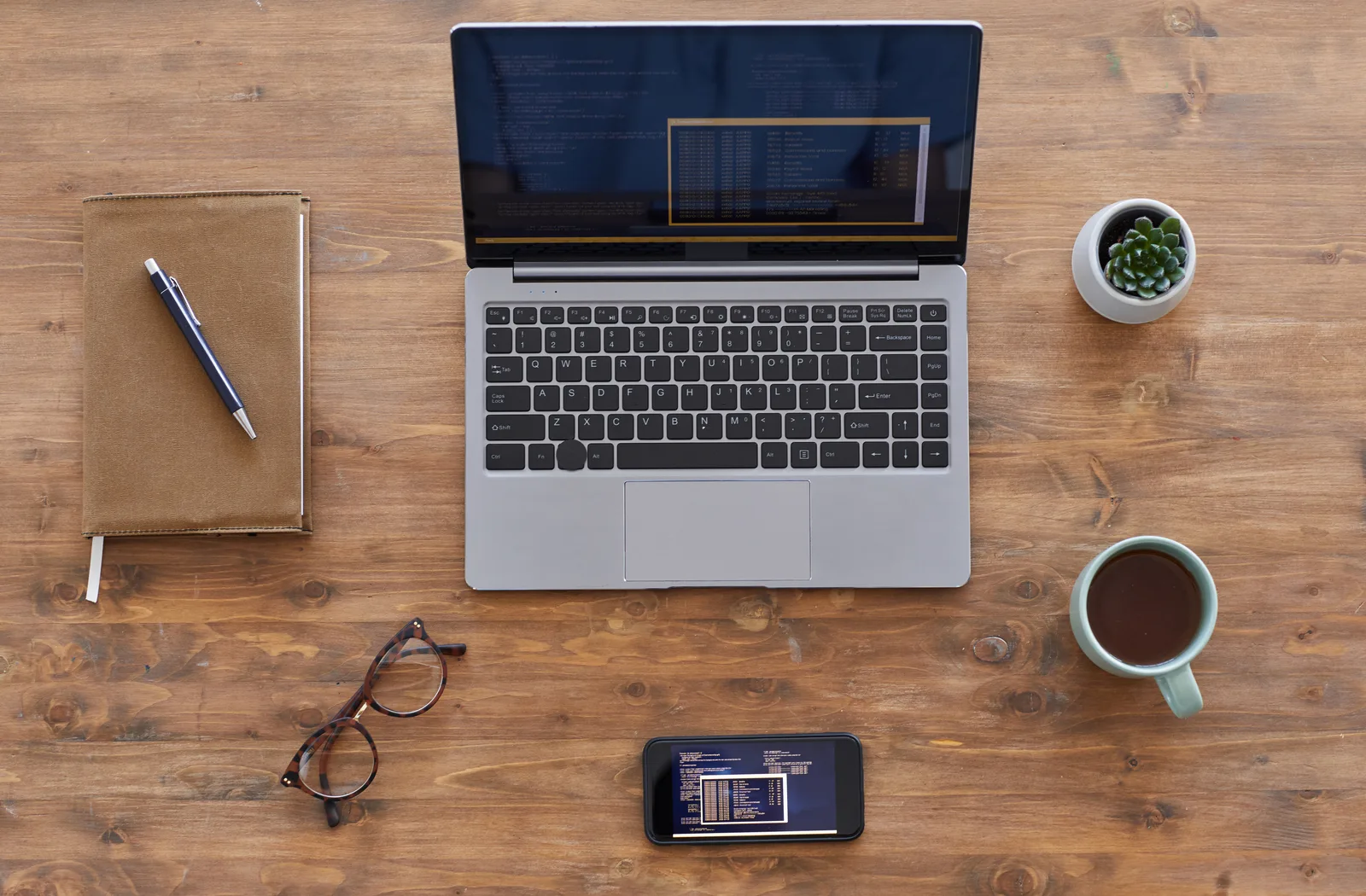 Laptop, Notizbuch, Brille und Kaffeetasse auf Holztisch, produktive Arbeitsumgebung