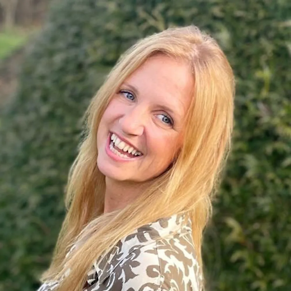 Porträt einer lachenden Frau mit rötlichblondem Haar vor grünem Hintergrund, Kundenstimme