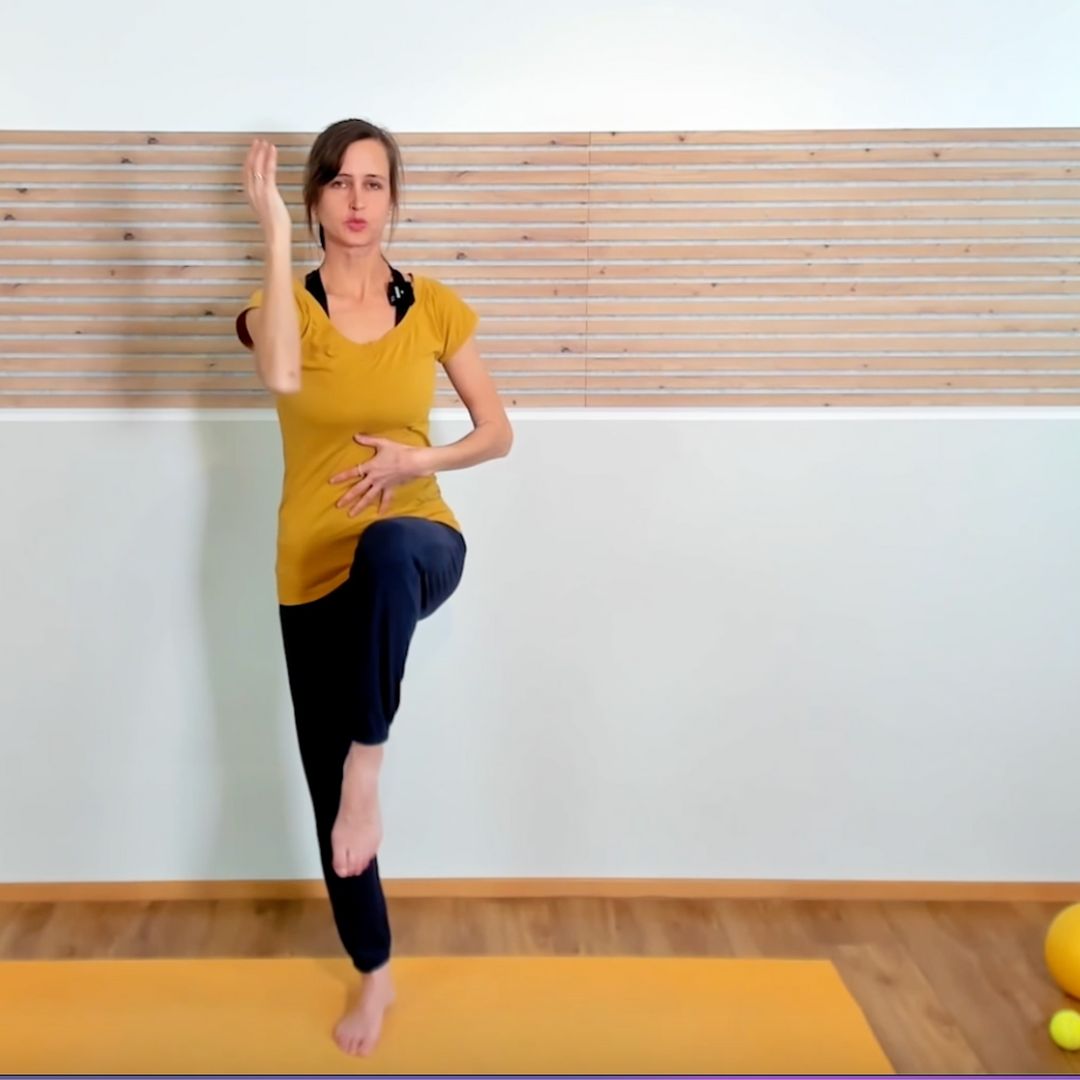 Schwangere Frau in gelbem Shirt macht Fitnessübung auf gelber Yogamatte