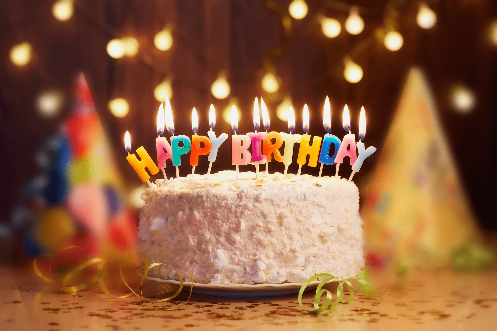 Geburtstagskuchen mit bunten Kerzen und 'Happy Birthday' Schriftzug