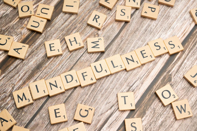 Scrabble-Buchstaben formen das Wort Mindfulness auf Holzuntergrund