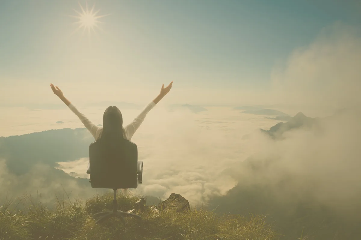 Frau mit erhobenen Armen auf Berggipfel über Wolkendecke