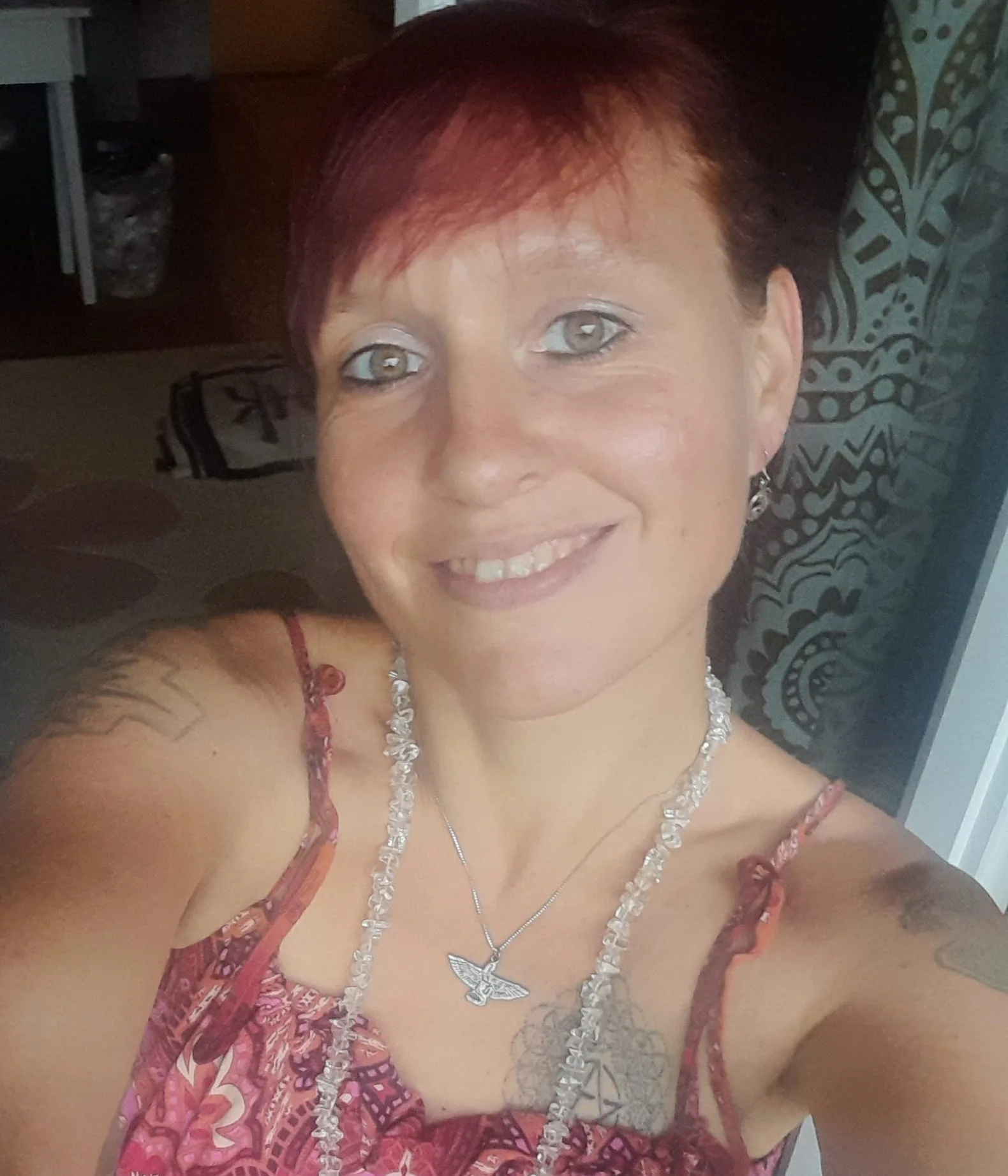 Porträt-Selfie einer Frau mit roten kurzen Haaren und silbernem Schmuck