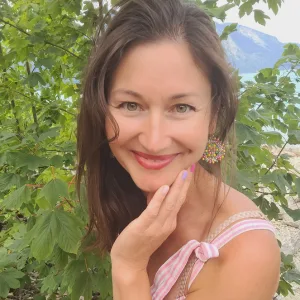 Sacred Woman Rising – Kurspaket heilige Weiblichkeit 32 Evgenia Halbach Porträt mit dunklem Haar vor grünem Laub