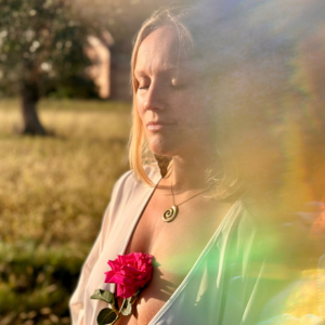Sacred Woman Rising – Kurspaket heilige Weiblichkeit 16 Caroline Hopp Porträt mit blondem Haar und rosa Blume in Gegenlicht