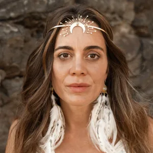 Sacred Woman Rising – Kurspaket heilige Weiblichkeit 11 Porträt von Jaqueline De Saunier mit Silber-Haarband und weißen Federn-Ohrringen vor Steinmauer