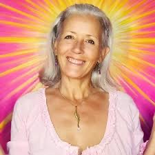 Sacred Woman Rising – Kurspaket heilige Weiblichkeit 36 Porträt von Sonja Ariel von Staden mit grauem Haar, rosa Oberteil vor farbenfroh strahlendem Hintergrund