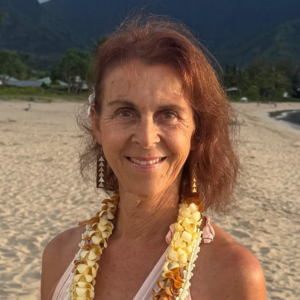 Sacred Woman Rising – Kurspaket heilige Weiblichkeit 10 Porträt von Margarete Bundschu mit rötlichem Haar und gelbem Lei-Schmuck am Strand