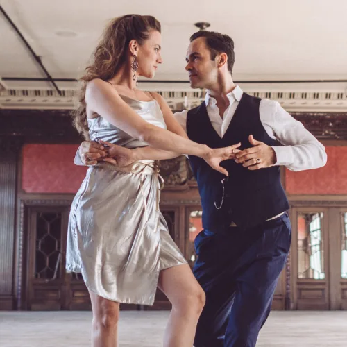 Tanzpaar beim Salsa On2 Tanzen in elegantem Setting mit klassischer Architektur im Hintergrund