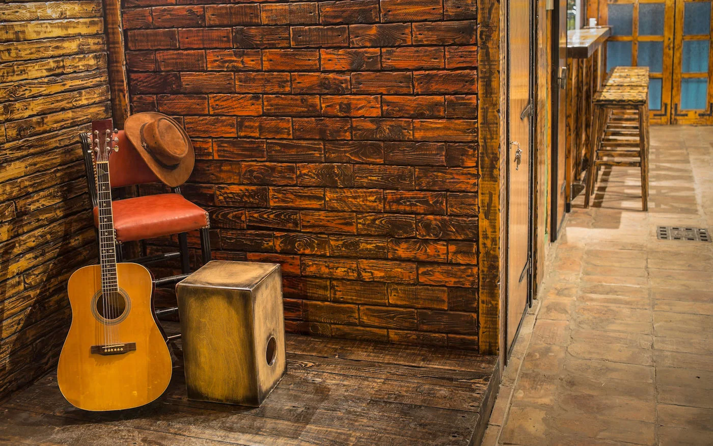 Musikinstrumente auf Holzbühne in Kneipe - Gitarre, Hut und Cajon
