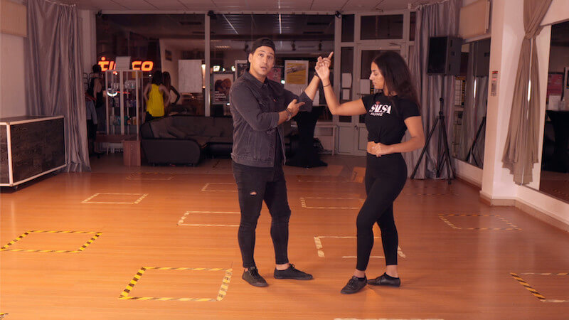 Tanzpaar führt Outside Turn Figur auf Tanzfläche mit Handposition auf