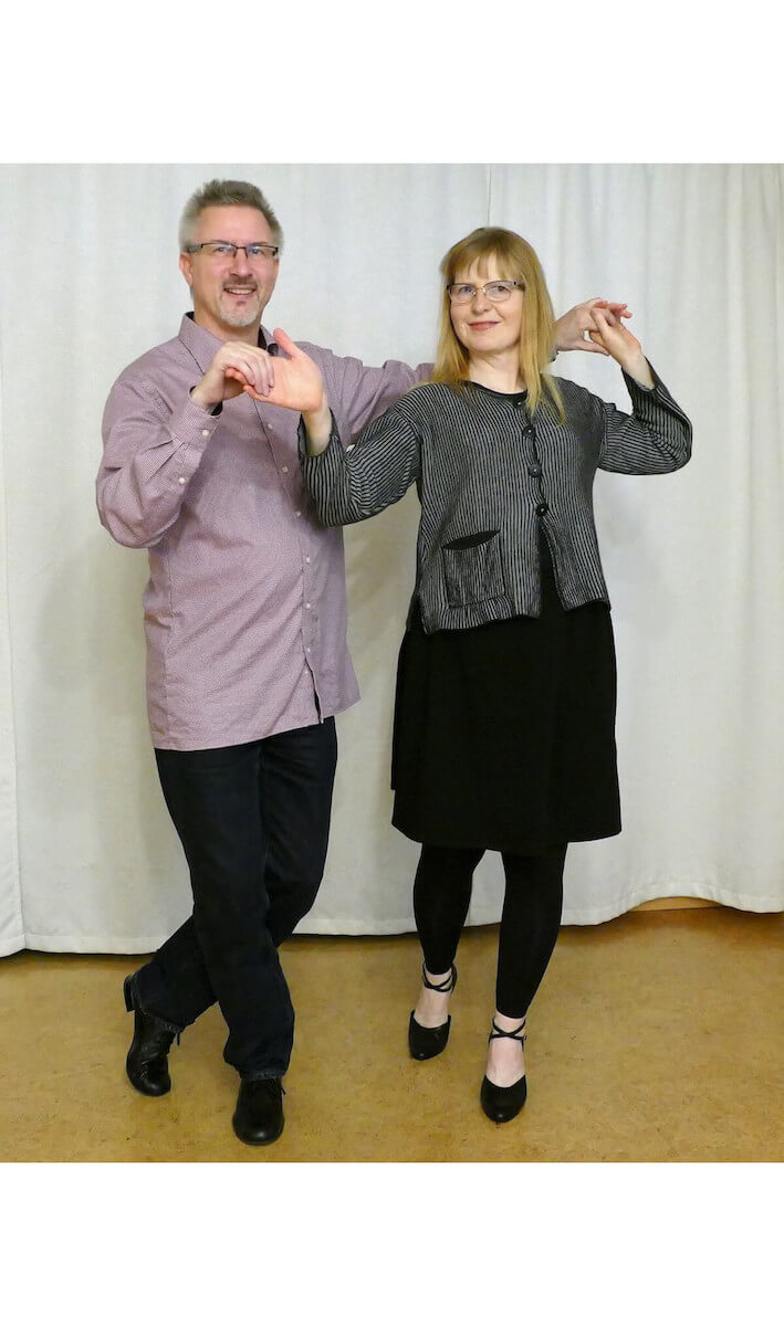 Kundenstimme Ehepaar tanzt Salsa in festlicher Kleidung mit ausgestreckten Armen