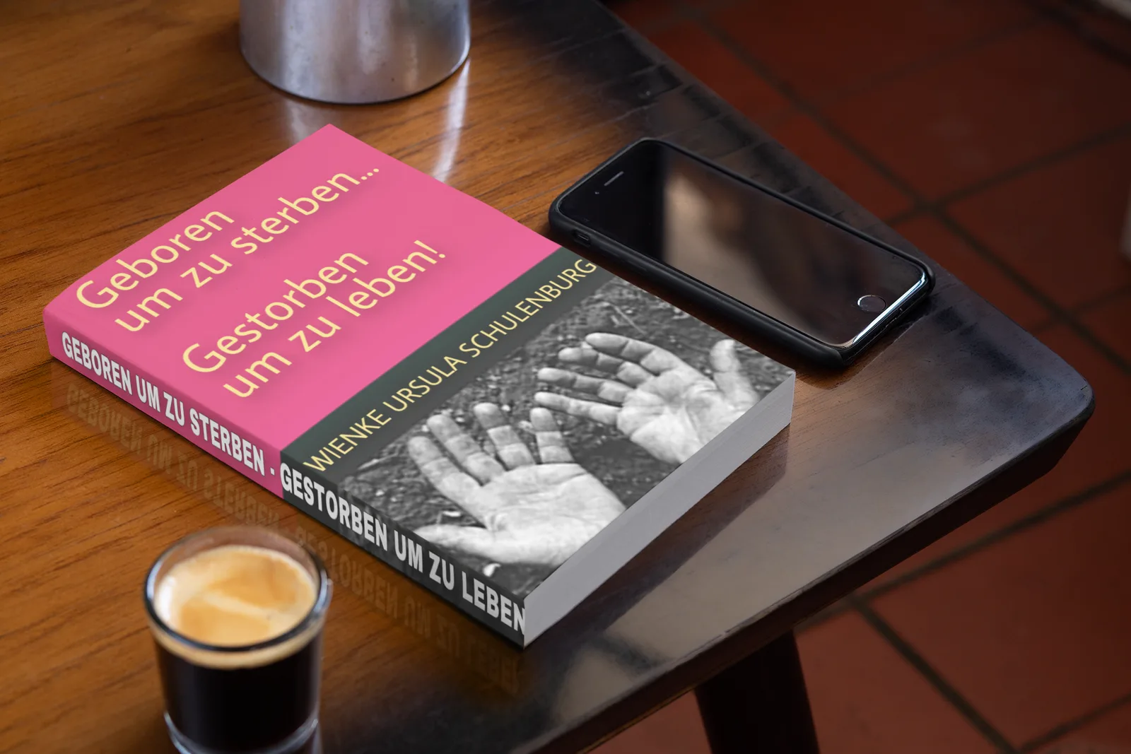 Buchcover Geboren um zu sterben mit Magnetfarbverlauf Pink-Grün, Schwarzweiß-Hände auf Holztisch