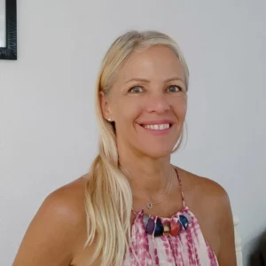 Porträt von Anja Aicher, blonde Frau mit Halskette, lächelnd vor weißem Hintergrund