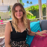 Porträt Frau Vanessa R. mit langen blonden Haaren vor tropischem Hintergrund