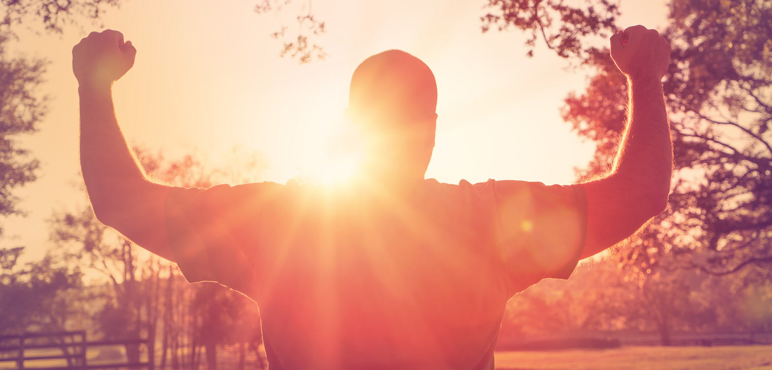 Silhouette eines Mannes mit Armen erhoben bei Sonnenaufgang in Natur