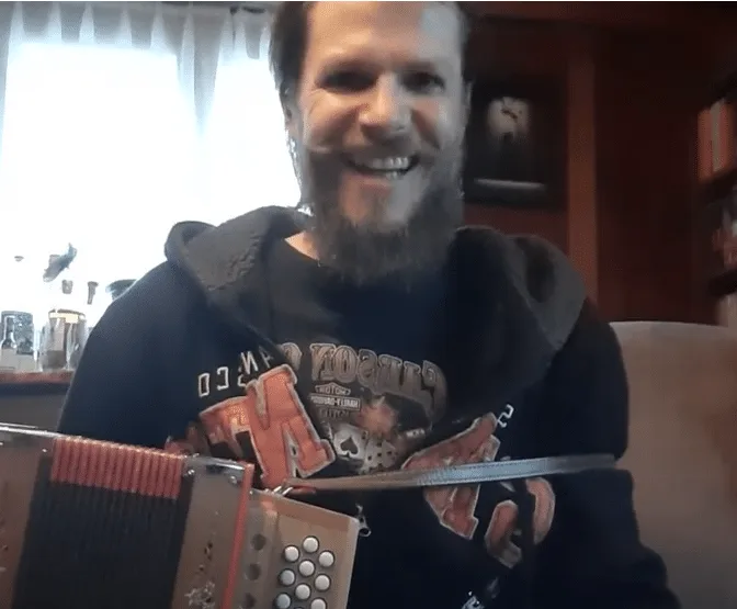 Screenshot eines lächelnden Mannes mit Schwyzerörgeli in Video-Aufnahme