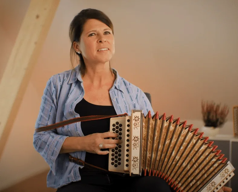 Gaby Wicki mit Schwyzerörgeli, Frau mit dunklen Haaren in blauem Hemd