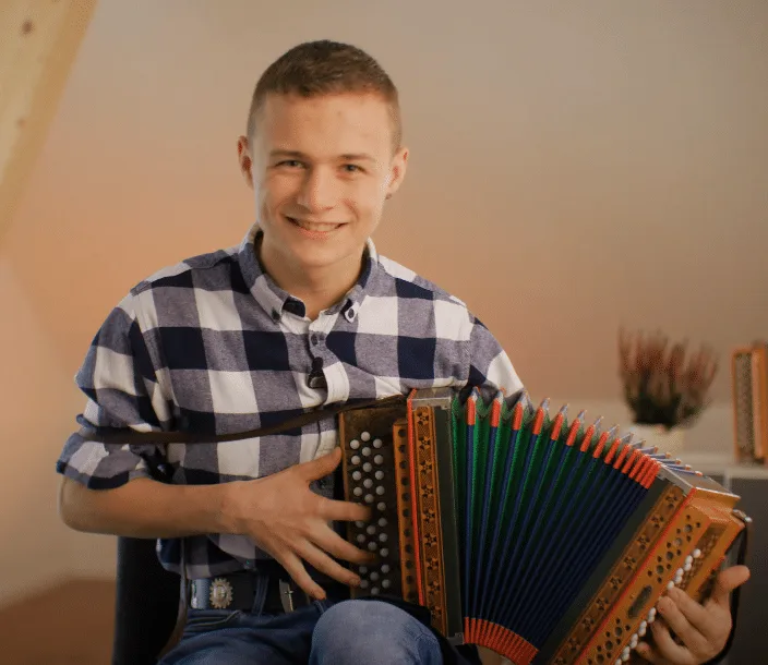 Leo Kaeslin mit Schwyzerörgeli, junger Mann in kariertem Hemd mit Akkordeon