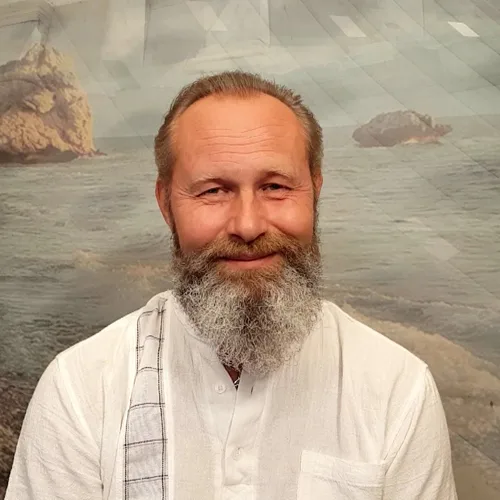 Mann mit Vollbart und grauem Haar vor Meerlandschaft, weißes Hemd