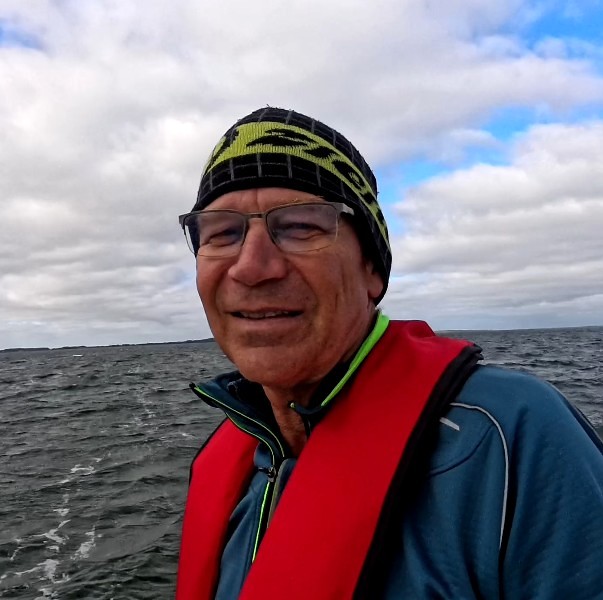 Ivan mit Brille und Mütze im roten Rettungsweste auf dem Meer, lächelnd