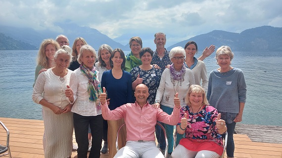 Gruppe von 15 Seminar-Teilnehmern am See in Weggis mit Bergen im Hintergrund