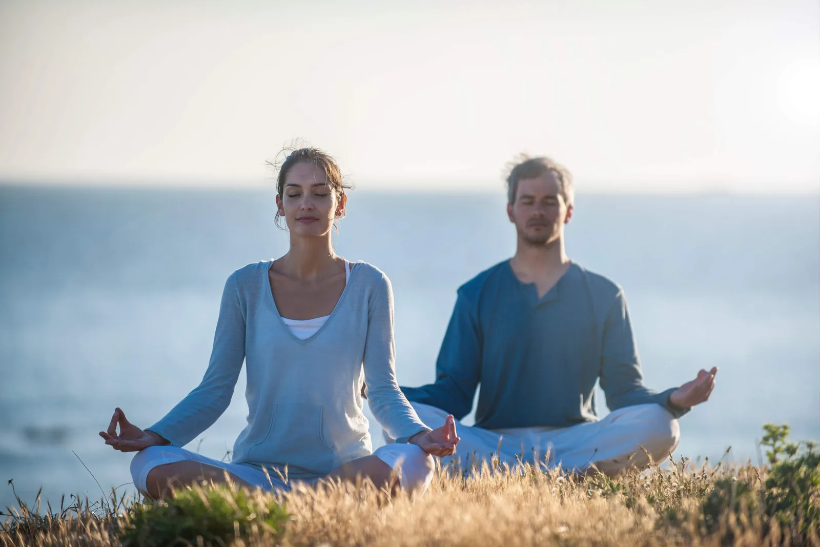 Zwei Personen in Meditation am Meer sitzend mit Meereshorizont