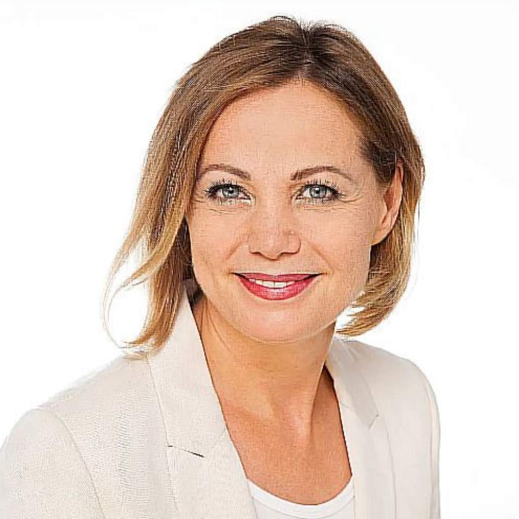 Porträt Christiana, Frau mit schulterlangen braunen Haaren, beigefarbener Jacke, weißem Top, lächelnd vor weißem Hintergrund