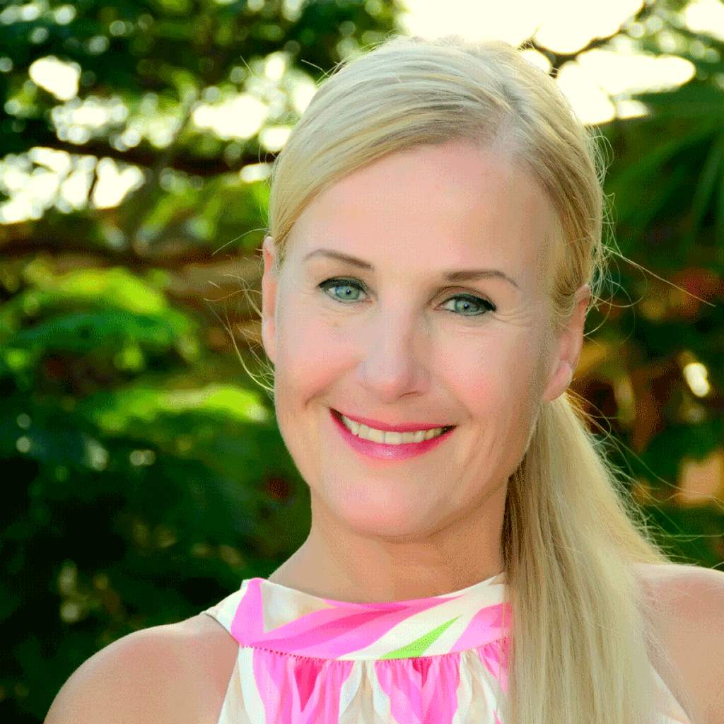 Porträt Tanja Matthoefer, blonde Frau, rosa und weiß gemustertes Top, grüner Hintergrund mit Laub