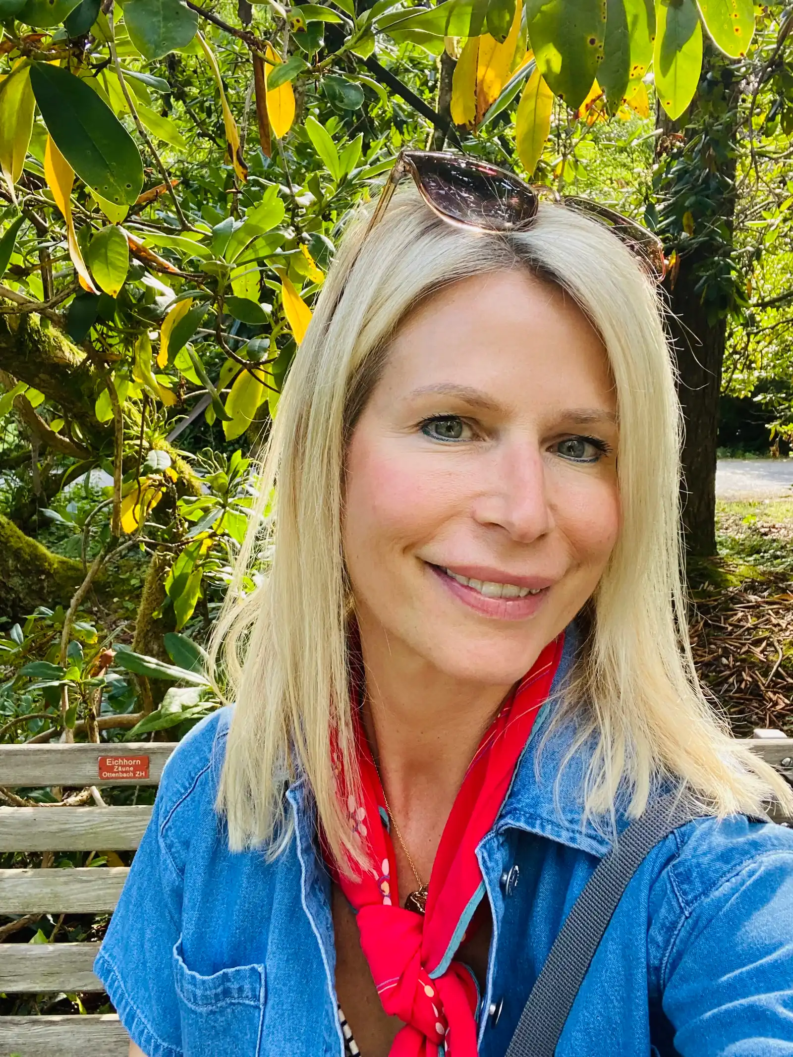 Porträt von Tanja Flütsch mit blauem Denim-Hemd und rotem Schal im Freien, lächelnd