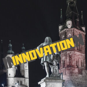 Statue in nächtlicher Altstadt mit gelbem Text INNOVATION