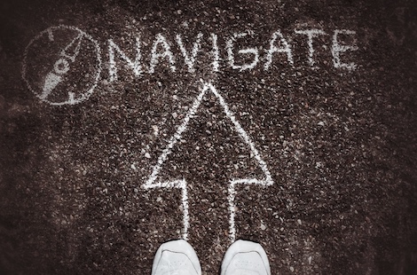 Selbstgeführte Stadtrallye Mainz 11 Asphalt mit Kreide-Pfeil und Text 'NAVIGATE', Schuhe von oben, Richtungsweisung