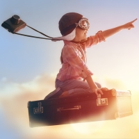 Hero-Banner mit Frau auf Kofferstapel, Hut und Fernglas, Arm ausgestreckt, Sonnenaufgang
