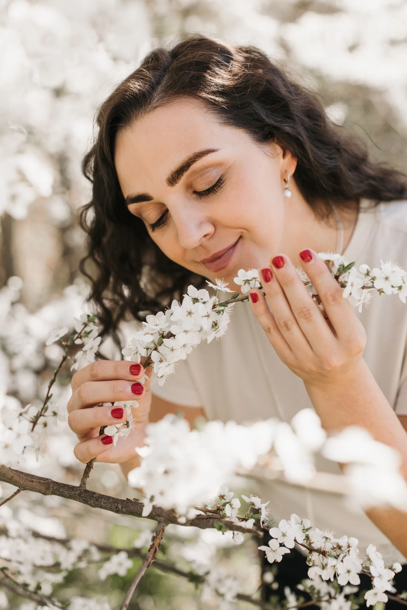 Selbstlernkurs Aromapraktiker*in von Manuela Hafner-Weber 1 Frau mit dunklen Haaren riecht an weißen Blüten, rote Nagelfarbe, Aromapraktiker E-Book Cover