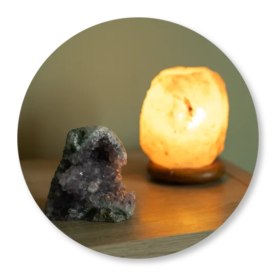 Stein-Mineralien neben leuchtender Salzlampe auf Holztisch