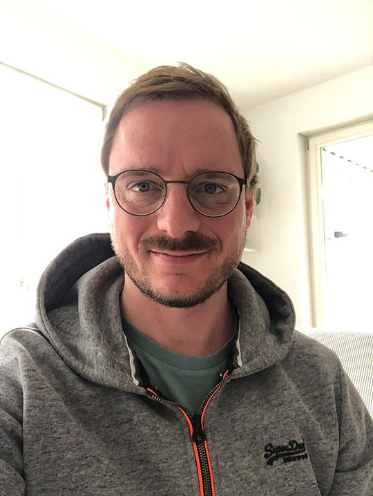 Markus mit Brille in grauer Jacke, Porträt in Innenraum