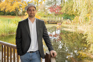 Pascal Schildknecht in Blazer an Holzgeländer mit Herbstlandschaft