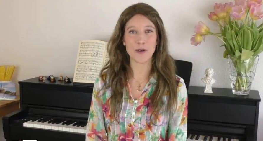 Susanna Proskura sitzt am Klavier in ihrem Studio mit Notenblättern und Blumen im Hintergrund