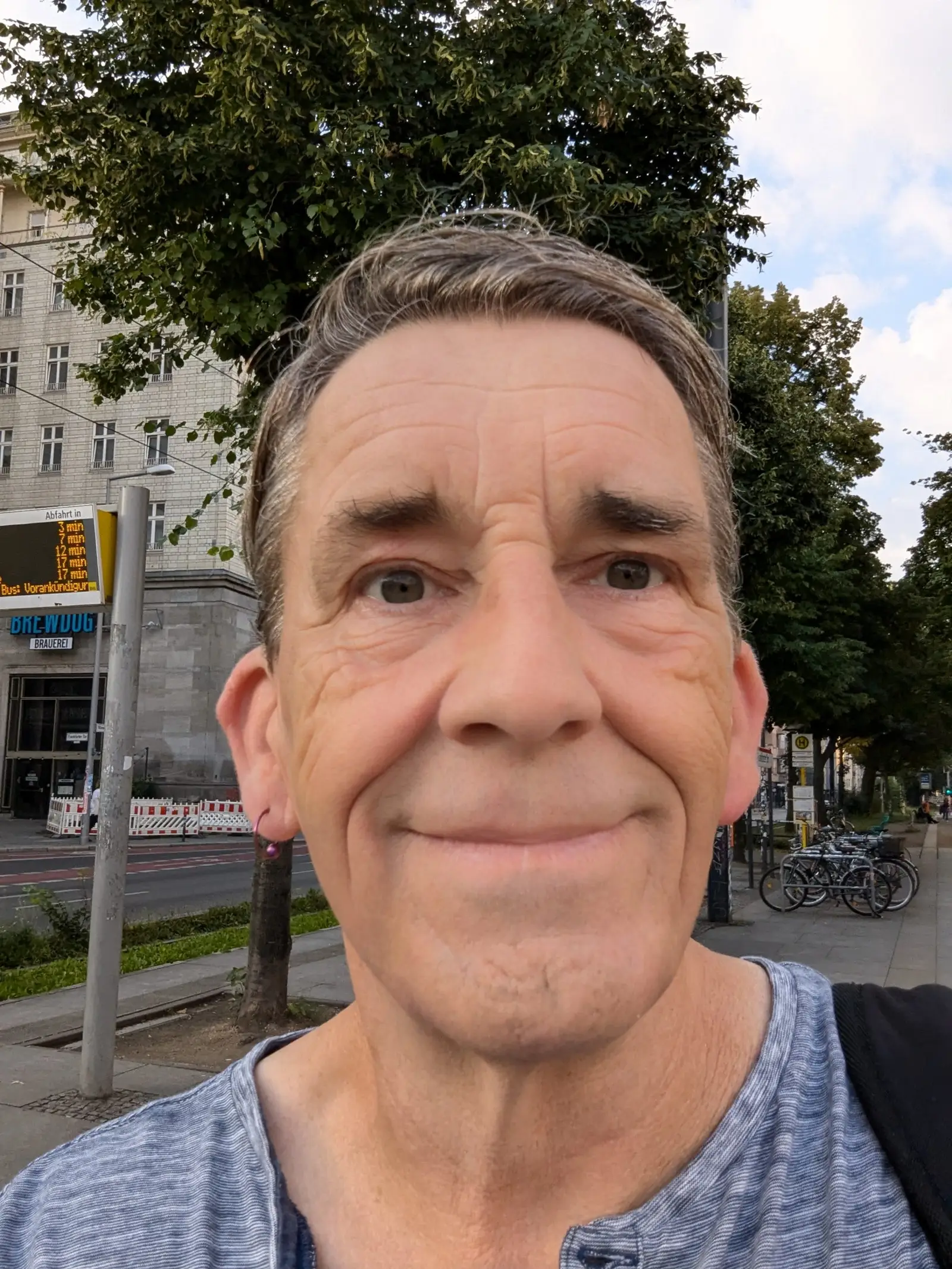 Mann mittleren Alters mit grauem Haar in hellblauem T-Shirt, Urban-Umgebung, Porträtaufnahme