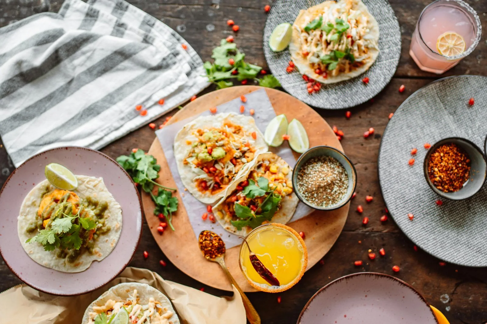 Tacos mit Fleisch, Koriander und Limetten auf Holztisch mit Getränken