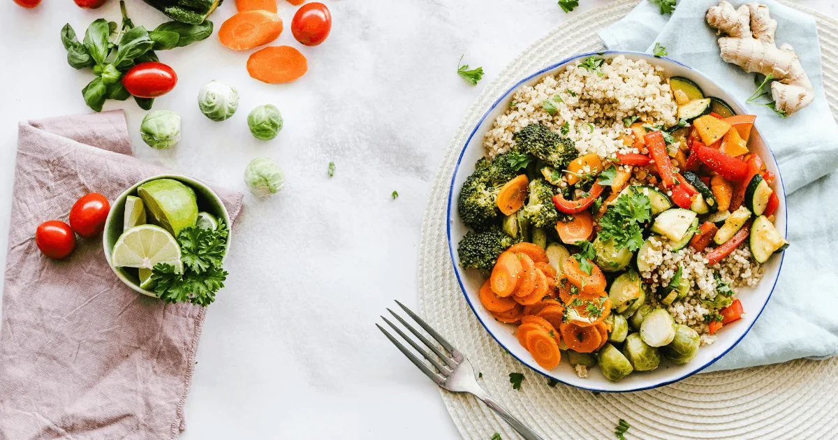 Gesundes Buddha-Bowl mit Quinoa, Brokkoli, Karotten, Zucchini und Gemüse auf weißem Teller