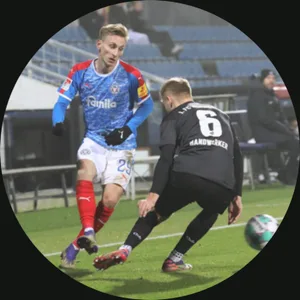 Junger Fußballspieler Joshua Mees in blauem Trikot mit gelbem Rand dribbelt mit Ball gegen Gegner