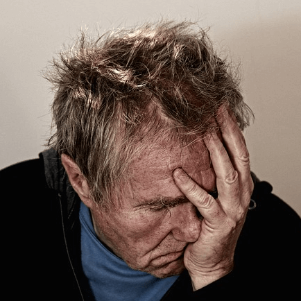 Mann mit Kopfschmerzen, Hand am Kopf, leidender Gesichtsausdruck
