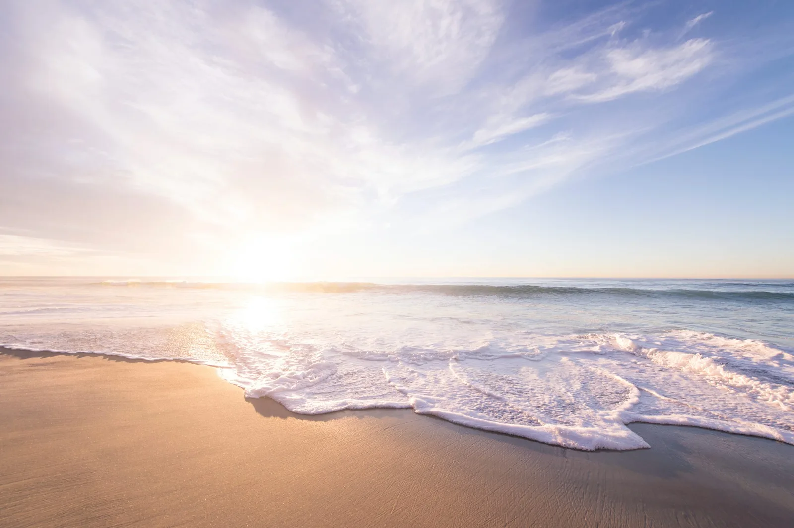Sonnenaufgang am Strand mit Wellen, Himmel und Sand
