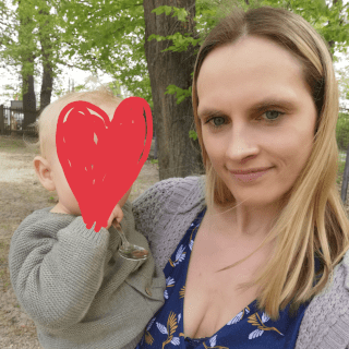 Porträtfoto einer Frau mit rotes Herz vor der Kamera haltend
