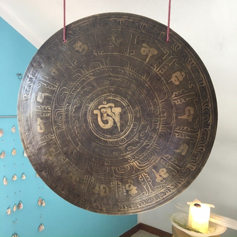 Hängender Gong mit Acht-Sylben-Mantra-Symbolen auf blauem Hintergrund