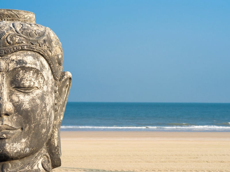Stein-Buddha-Kopf vor Strand und Meereshorizont